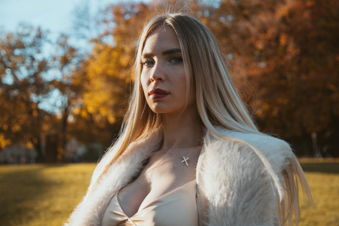 Portrait of elegant woman in fur coat in Munich park during fall. Beautiful autumn colors.